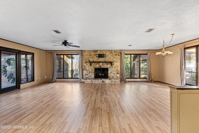 unfurnished living room featuring a stone fireplace, plenty of natural light, and light hardwood / wood-style flooring