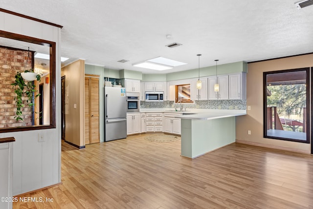 kitchen featuring sink, white cabinetry, hanging light fixtures, kitchen peninsula, and stainless steel appliances