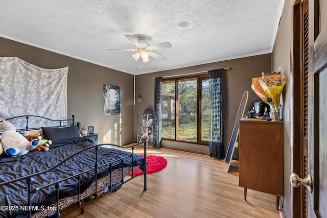 bedroom with hardwood / wood-style flooring, ceiling fan, and a textured ceiling