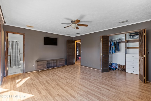 unfurnished bedroom featuring crown molding, a closet, light hardwood / wood-style flooring, and a textured ceiling