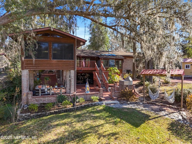 back of house with a wooden deck, a sunroom, a patio, and a lawn