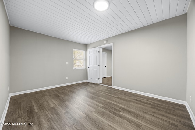 spare room featuring dark wood-type flooring and wood ceiling