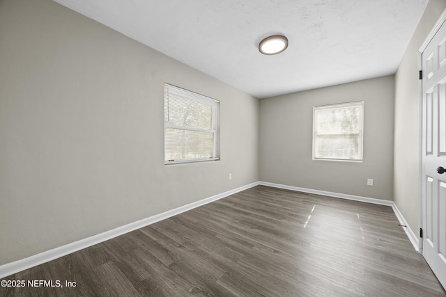 unfurnished bedroom featuring multiple windows and dark hardwood / wood-style floors