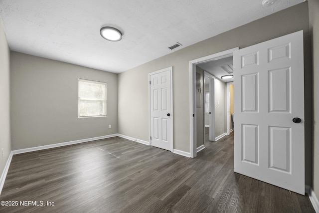 empty room featuring dark wood-type flooring and a textured ceiling