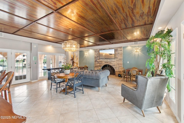 interior space with french doors, wood ceiling, a chandelier, light tile patterned floors, and a large fireplace