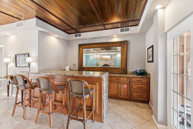 bar with sink, light stone counters, wood ceiling, and light tile patterned floors