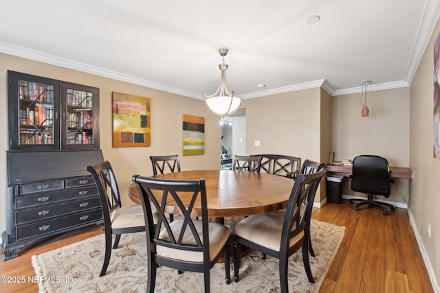 dining area with crown molding and light hardwood / wood-style flooring