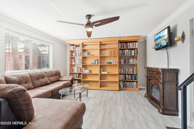 living room featuring ceiling fan, wood-type flooring, ornamental molding, and a textured ceiling