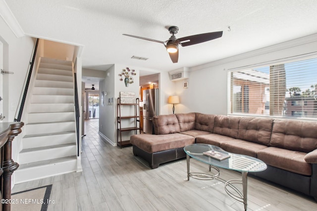 living room with ceiling fan, a textured ceiling, and light wood-type flooring