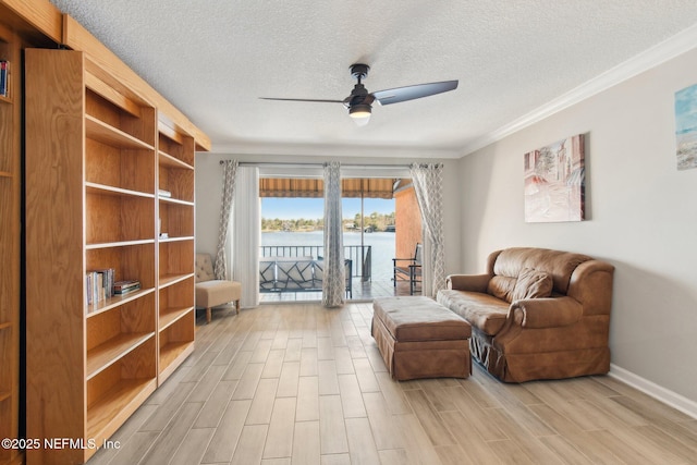 sitting room featuring crown molding, a textured ceiling, ceiling fan, and a water view