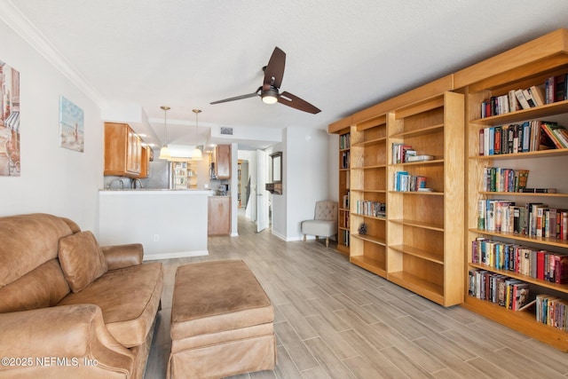 living room with ceiling fan, ornamental molding, a textured ceiling, and light wood-type flooring