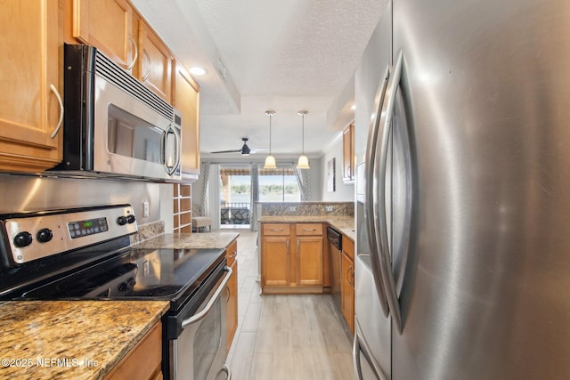 kitchen with light stone counters, a textured ceiling, appliances with stainless steel finishes, pendant lighting, and ceiling fan