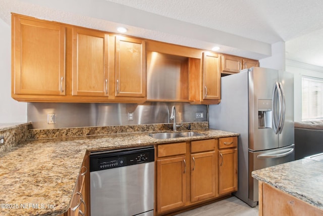 kitchen featuring light stone counters, sink, stainless steel appliances, and a textured ceiling