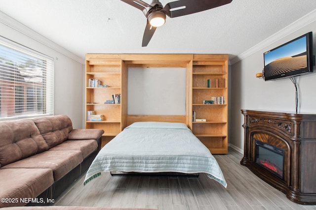 bedroom featuring ceiling fan, crown molding, a textured ceiling, and light wood-type flooring