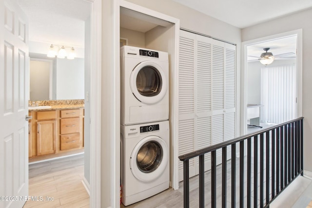 clothes washing area with stacked washer / drying machine and light hardwood / wood-style flooring