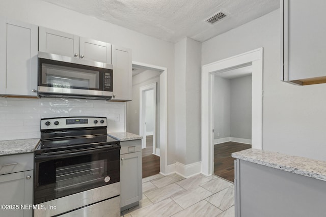 kitchen with stainless steel appliances, light stone countertops, and backsplash