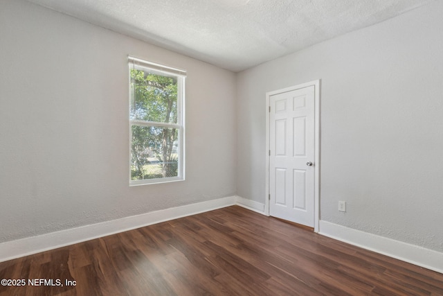 spare room featuring dark wood-type flooring and a textured ceiling