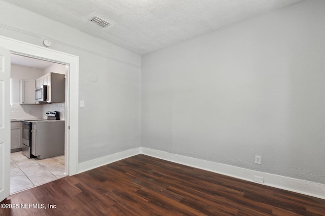 unfurnished room with a textured ceiling and light wood-type flooring