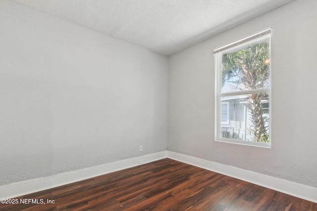 spare room with a healthy amount of sunlight, dark wood-type flooring, and a textured ceiling