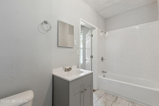 full bathroom with tiled shower / bath combo, vanity, a textured ceiling, and toilet