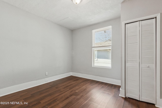 unfurnished bedroom with a textured ceiling, dark hardwood / wood-style flooring, and a closet