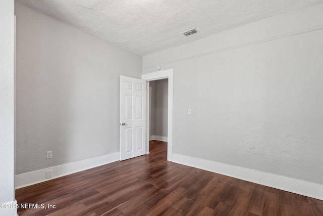 unfurnished room featuring dark hardwood / wood-style flooring and a textured ceiling