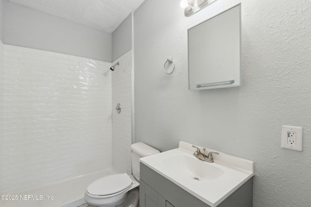 bathroom featuring vanity, toilet, and tiled shower