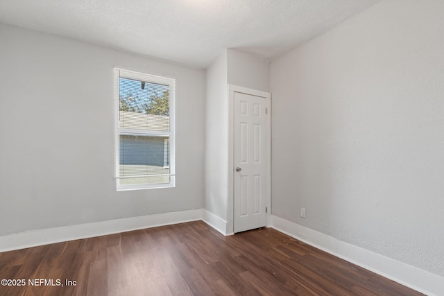 empty room with dark wood-type flooring and a textured ceiling