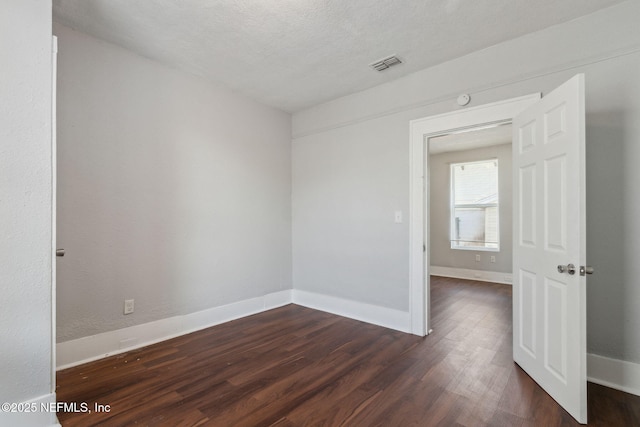 spare room featuring dark hardwood / wood-style flooring and a textured ceiling