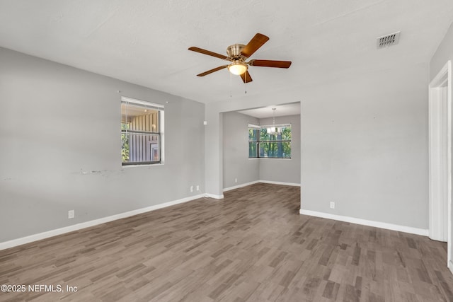 unfurnished room featuring hardwood / wood-style flooring and ceiling fan with notable chandelier