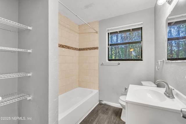 full bathroom featuring hardwood / wood-style floors, tiled shower / bath combo, a wealth of natural light, and toilet