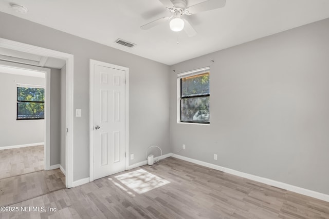 unfurnished bedroom featuring multiple windows, ceiling fan, and light hardwood / wood-style flooring