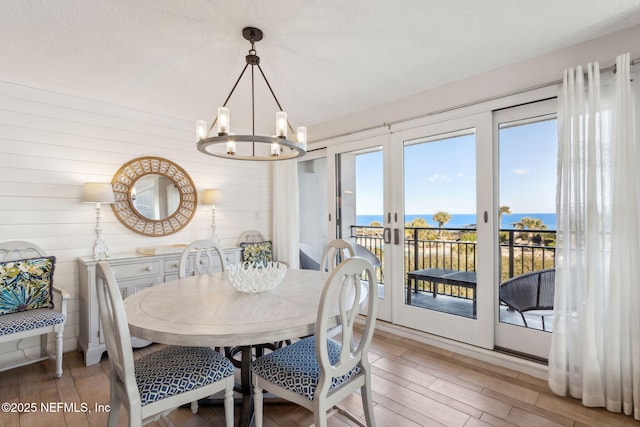 dining room with a water view, wood-type flooring, and a notable chandelier