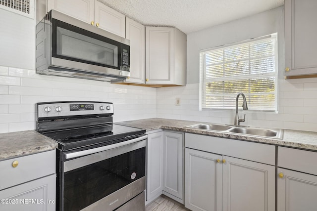 kitchen with stainless steel appliances, gray cabinets, and sink