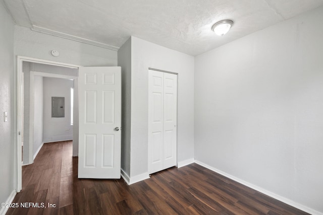 unfurnished bedroom with dark wood-type flooring, electric panel, and a closet