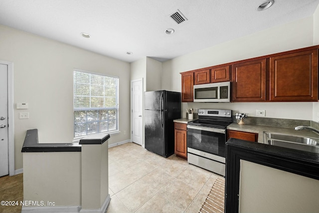 kitchen featuring sink, light tile patterned floors, kitchen peninsula, and appliances with stainless steel finishes