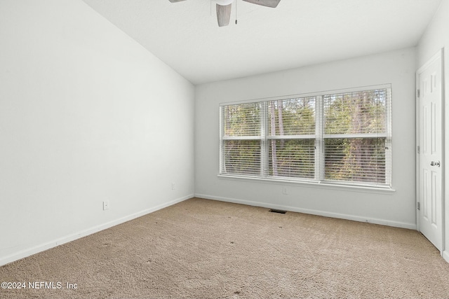 carpeted spare room featuring vaulted ceiling and ceiling fan