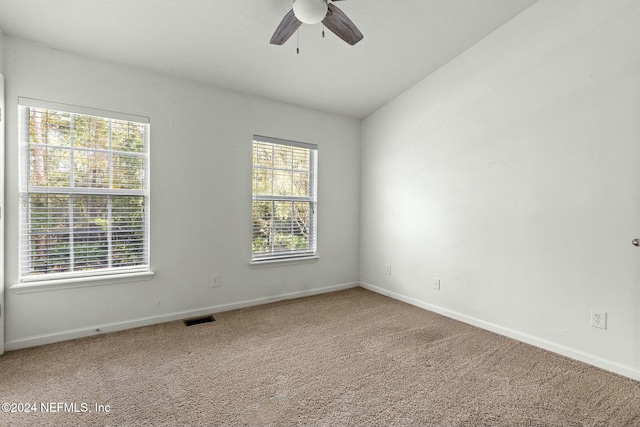 empty room with lofted ceiling, ceiling fan, and carpet flooring