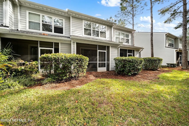 rear view of property featuring a yard and a sunroom