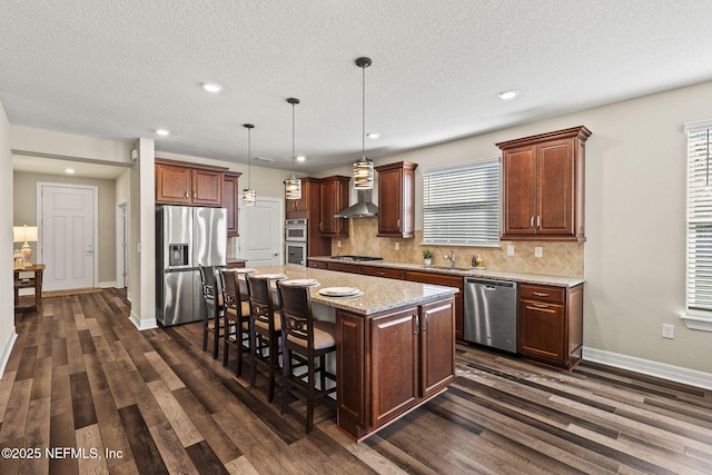 kitchen featuring dark wood-type flooring, appliances with stainless steel finishes, hanging light fixtures, a kitchen breakfast bar, and a center island