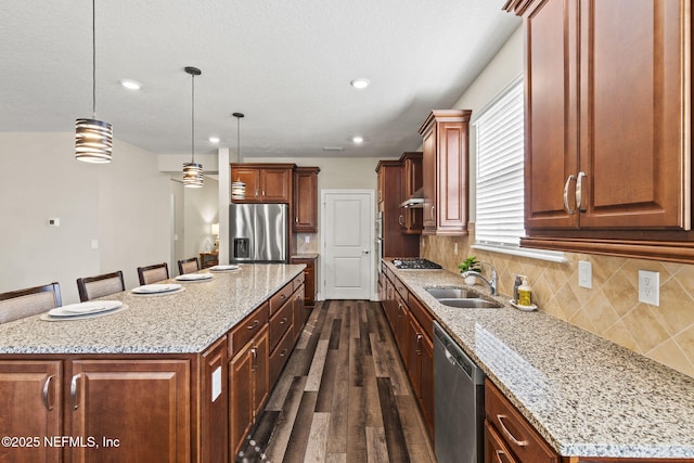 kitchen with appliances with stainless steel finishes, a center island, sink, and decorative light fixtures