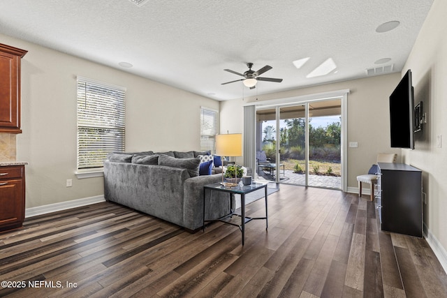 living room with plenty of natural light, dark wood-type flooring, and a textured ceiling