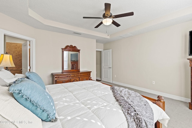 bedroom with ceiling fan, a raised ceiling, a textured ceiling, and carpet flooring