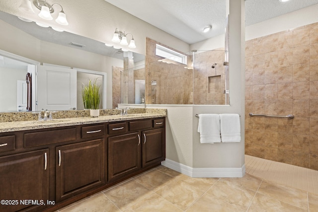 bathroom with vanity, tile patterned flooring, a textured ceiling, and tiled shower