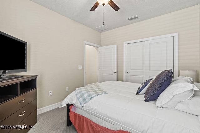 carpeted bedroom with ceiling fan, a closet, and a textured ceiling