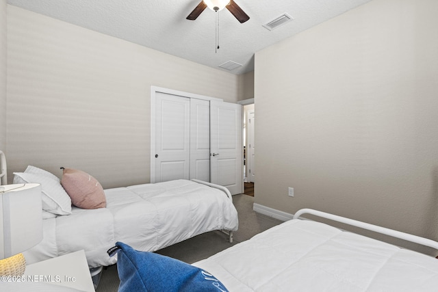 bedroom with a textured ceiling, a closet, ceiling fan, and carpet