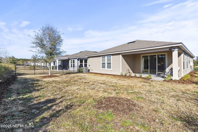 rear view of property with central AC and a lawn