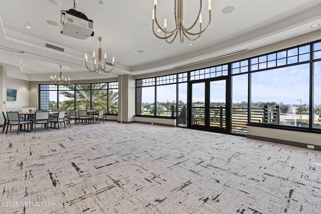 interior space featuring a healthy amount of sunlight, a notable chandelier, and a tray ceiling