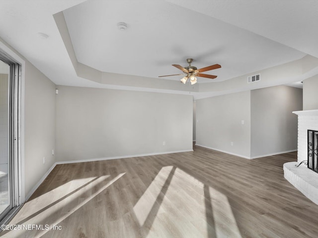 unfurnished living room with ceiling fan, wood-type flooring, and a brick fireplace