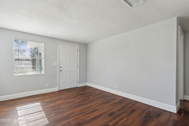 empty room featuring dark hardwood / wood-style floors and a textured ceiling